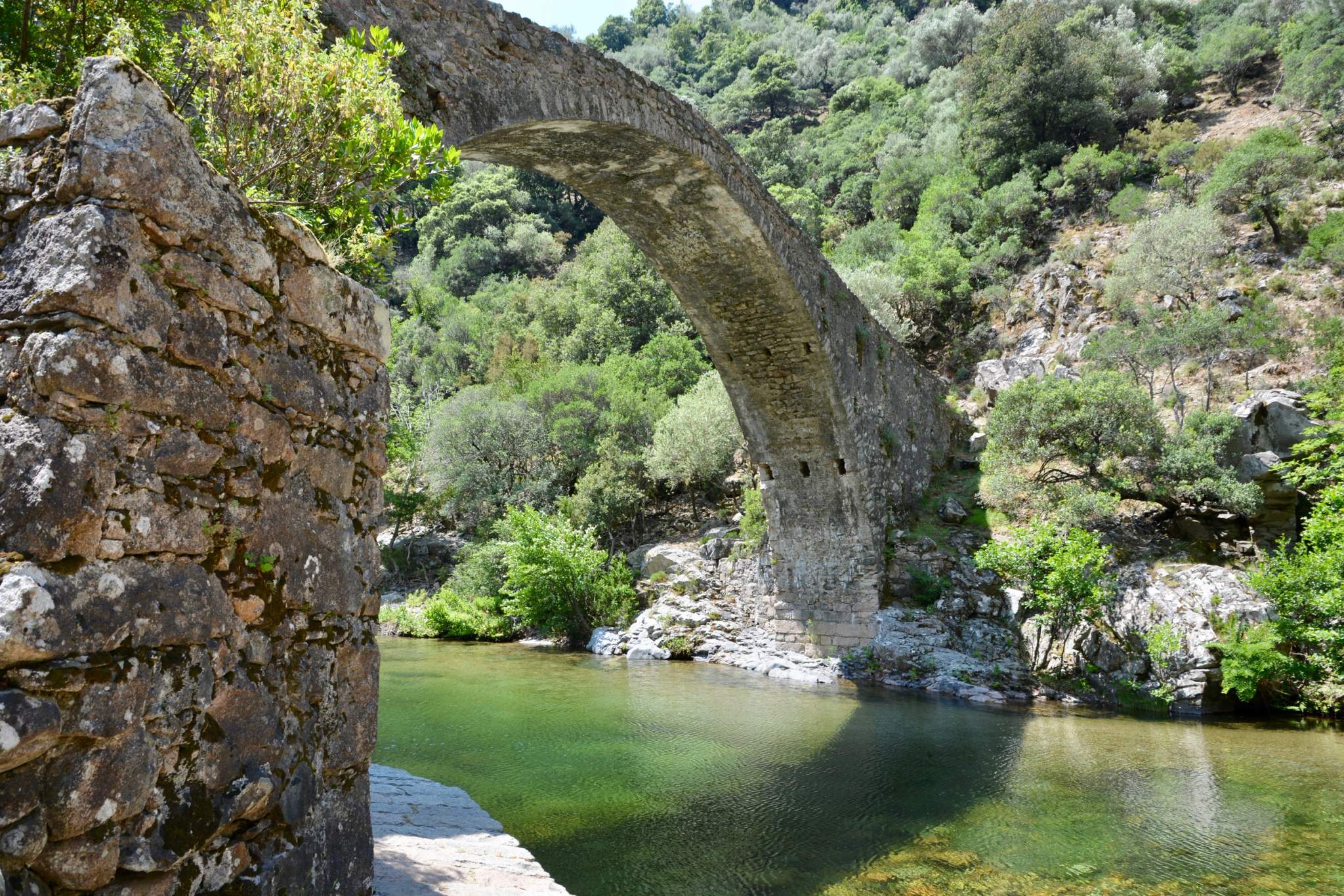 Genoese stone bridge over a clear-water river in Corsica.