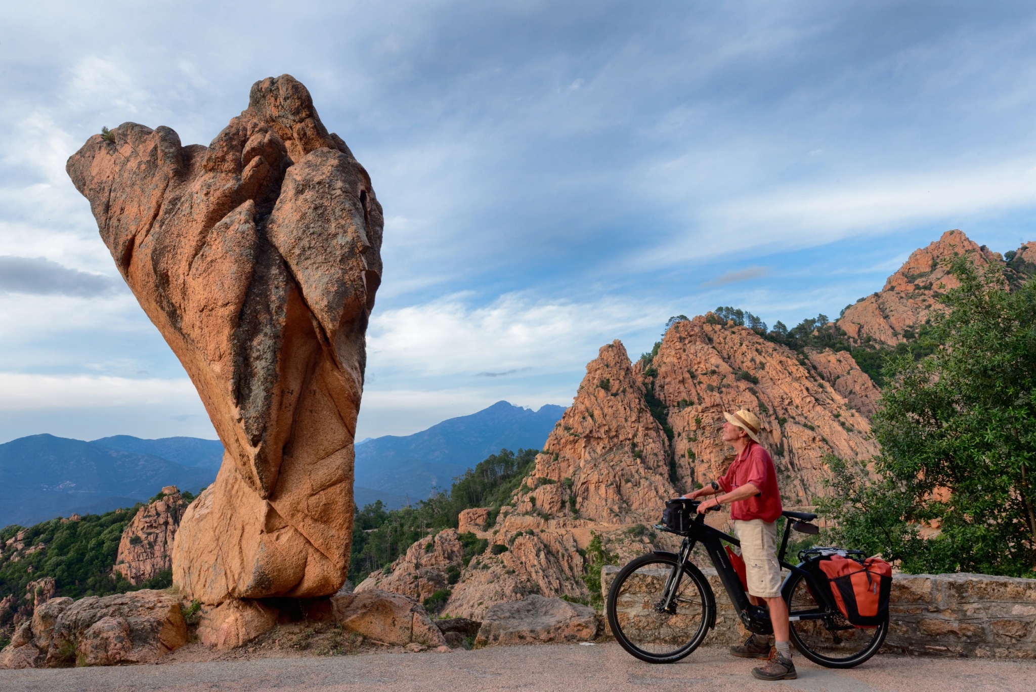 Cyclist in front of the rock formations of the Calanques de Piana in Corsica.
