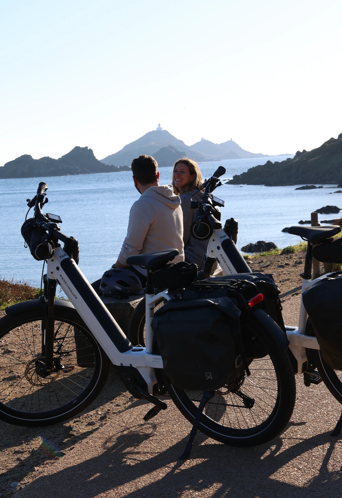 Two travelers admiring the sunset over the mountains and the sea in Corsica.